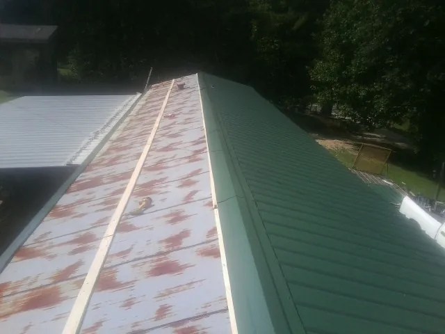 Old rusted panels beside newly installed green metal roofing — Wind Damage Roof Repair by Roofing Brothers in Bascom