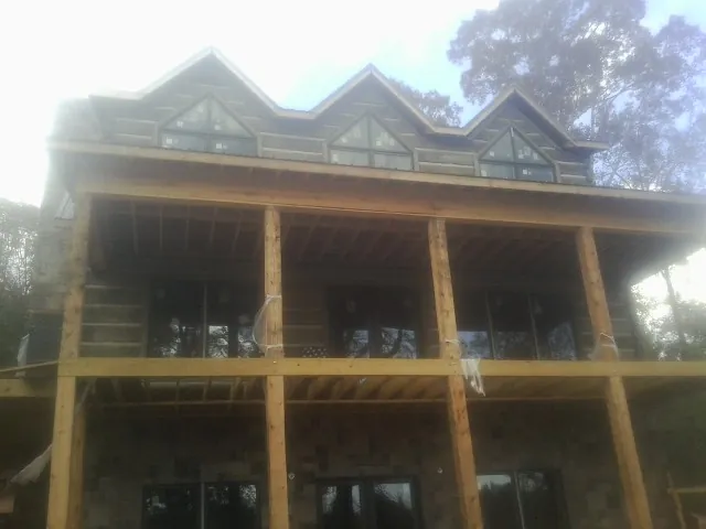 Dormers and porch framing on a large log home under construction — Roof Coating work by our crew in Bascom